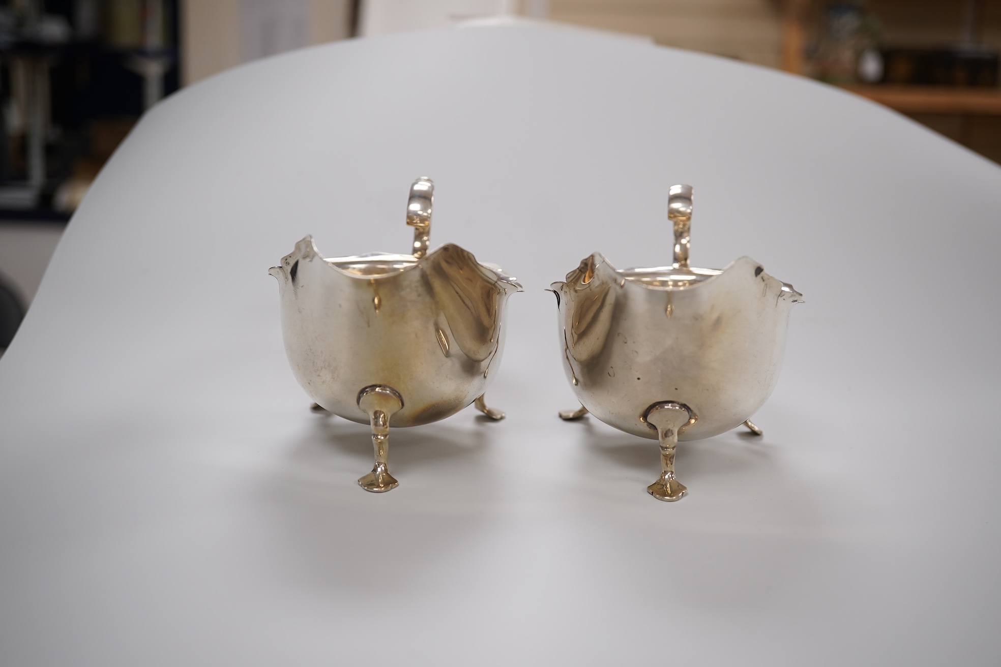 A pair of George V silver sauce boats, with flying scroll handles and pair of matching sauce ladles, Martin, Hall & Co, Sheffield, 1922/3, 10.1oz.